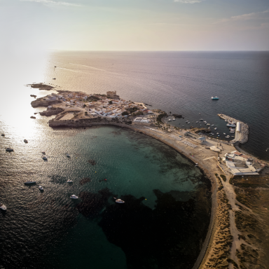 Vista aérea de una costa con casas blancas, barcos y mar tranquilo.